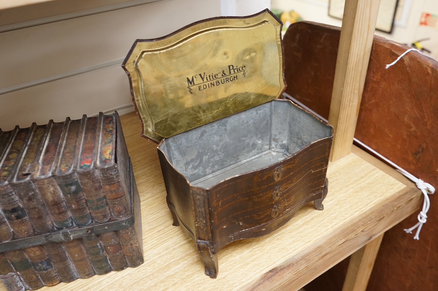 A Huntley and Palmer biscuit tin, modelled as a set of books and and two Mcvitie and Price tins modelled as French chests, tallest 16cm